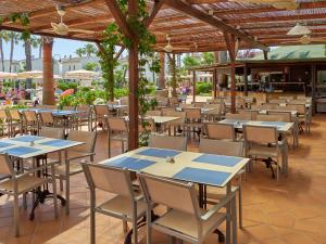穆罗海滩BQ阿尔库迪亚太阳村酒店的庭院里空着的餐馆,配有桌椅