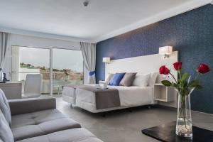 甘迪亚海滩埃斯金索滨海山庄公寓式酒店的一间卧室配有一张床和一个红色玫瑰花瓶
