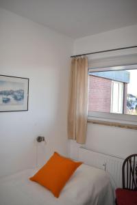 达默Haus-am-Deich-Wohnung-12的一间卧室配有一张带橙色枕头的床和窗户