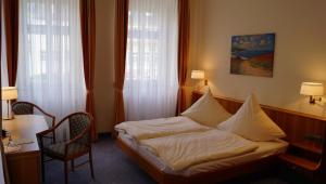 Waldheim金狮酒店的一间卧室配有一张床和一把椅子,还有两个窗户