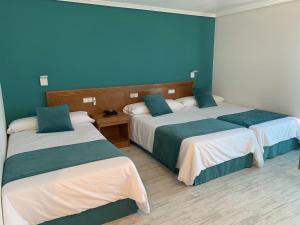 托米尼奥努埃瓦科利纳酒店的两张位于酒店客房的床,拥有蓝色的墙壁