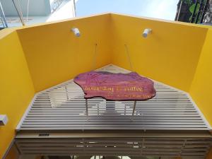 芹苴K2 Homestay & Coffee的黄色墙顶上的粉红色伞