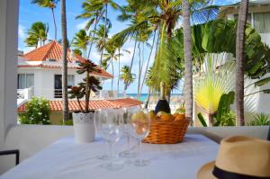 蓬塔卡纳Beach Villas & Apartments Larimar的一张桌子,上面放有酒杯和一篮水果