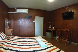 拉差汶里阿若斯瑞泰拉旅馆的卧室配有一张床,墙上配有电视。