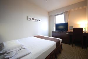 山口Kokusai Hotel Yamaguchi的酒店客房配有一张床和一张书桌及一台电视