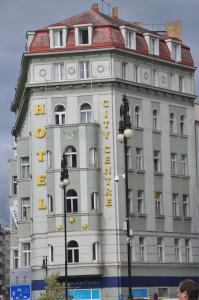 布拉格城市中心酒店的白色的建筑,上面有黄色的标志