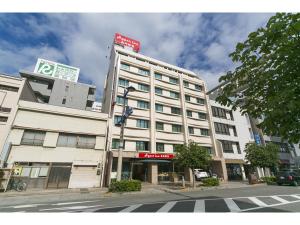 高松Hyper-inn Takamatsu Ekimae的一条有人行道的城市街道上白色的大建筑