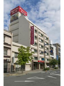 高松Hyper-inn Takamatsu Ekimae的一座白色的大建筑,上面有红色的标志
