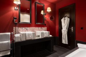 海牙Hotel Des Indes The Hague的浴室设有红色的墙壁和架子上的白色浴袍