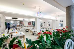 利尼亚诺萨比亚多罗皇宫酒店的一间设有桌椅的餐厅,种植了植物