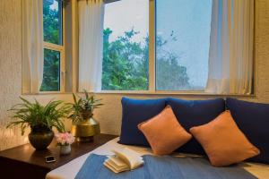 罗纳瓦拉EL Lodge by StayVista - Pool, lawn, and a charming gazebo for your perfect getaway的一张带枕头的沙发、桌子和窗户