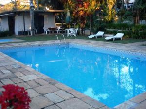 伊比乌纳Hotel Fazenda Bandeirantes的蓝色游泳池,带两把椅子和房子