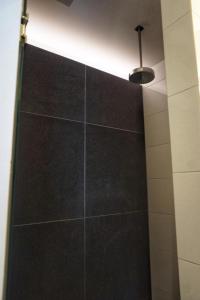 博克斯特尔Bed & Wellness Boxtel, luxe kamer met airco en eigen badkamer的黑色瓷砖墙和灯的淋浴