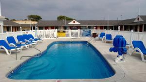 萨默斯波因特Passport Inn Somers Point - Somers Point的一个带蓝色椅子和泳池景的游泳池