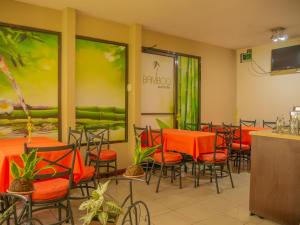 阿拉胡埃拉Hotel Bamboo Aeropuerto的用餐室配有橙色桌椅