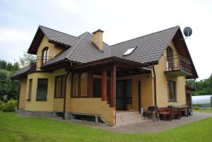 波拉齐克Dom Gościnny的黄色的房子,有黑色的屋顶和一张桌子