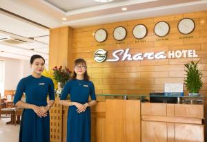 岘港Shara Hotel Da Nang的两名妇女站在一个沙萨旅馆前