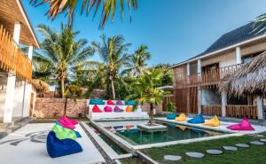 龙目岛库塔Kaniu Capsule Hostel的别墅后院的游泳池配有色彩缤纷的枕头