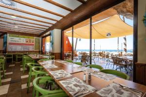 贝纳尔马德纳假日世界度假酒店的餐厅设有木桌和绿色椅子