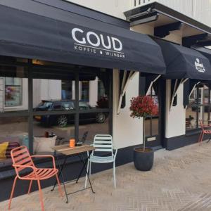 滨海卡特韦克Kamers van Goud的餐厅在黑伞下配有桌椅