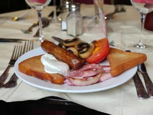 桑德维奇The Five Bells, Eastry的餐桌上放着一盘带香肠和蔬菜的食物