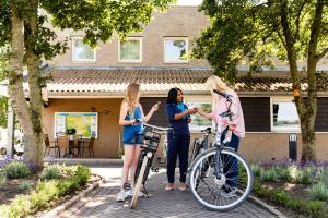 IJssellaanTopParken – Parc IJsselhoeve的三名妇女站在房子前面,她们有自行车