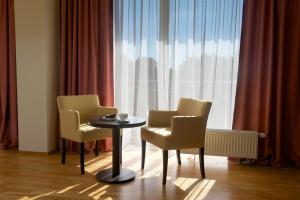 帕兰加波罗的酒店的窗户前设有2把椅子和1张桌子的房间