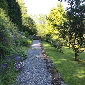 斯特拉西尔Mews Cottage Ardoch Lodge Strathyre的花园里种有树木和鲜花的碎石路