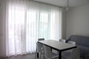 利多迪耶索罗West beach 3的餐桌、白色椅子和大窗户