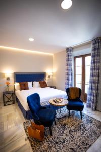 加的斯Plazuela del Carbón Suites的酒店客房配有一张床、两把椅子和一张桌子