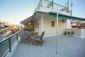 雅典ivannas penthouse的阳台配有桌椅和遮阳伞。