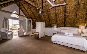 约翰内斯堡绿色公园庄园酒店的卧室设有白色的床和木制天花板。