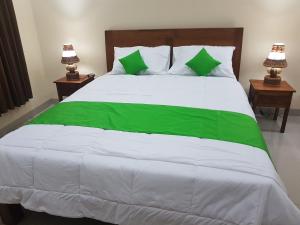 乌布Gusti Room的一张配有绿色和白色床单的大床和两盏灯