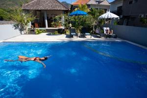 艾湄湾Bali Dive Resort Amed的一个人在大型蓝色游泳池游泳
