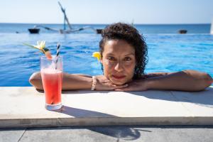 艾湄湾Bali Dive Resort Amed的游泳池里的女人喝一杯