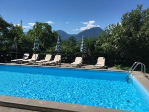 梅拉诺比奇勒公寓酒店的一个带椅子的游泳池,背景是山脉