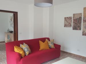 大圣玛丽亚Appartamento la Canvetta的客厅里红色的沙发,配有黄色枕头