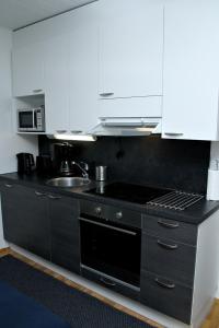 约恩苏Kotimaailma Apartments Joensuu - Koulukatu 21的厨房配有白色橱柜和黑炉灶烤箱。
