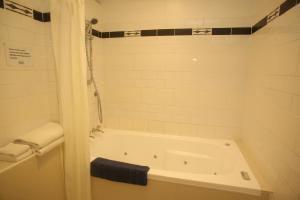 旺格努伊The Grand Hotel Wanganui的白色的浴室设有浴缸和淋浴。