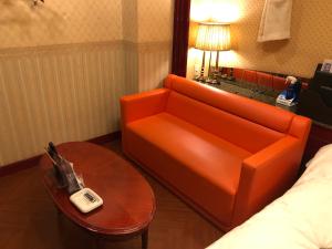 长崎长崎小型俱乐部情趣酒店（仅限成人）的橙色的沙发和酒店客房内的桌子