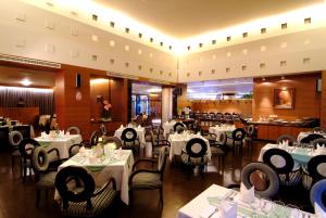 高雄京城大飯店的一间设有白色桌椅的用餐室和一间餐厅