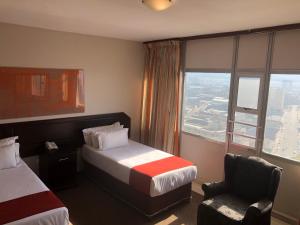 德班Coastlands Durban Self Catering Holiday Apartments的酒店的客房 - 带一张床、椅子和窗户