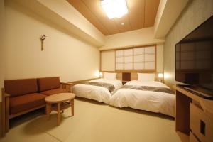 奈良御宿诺诺奈良天然温泉酒店的客房设有两张床、一张沙发和一台电视。