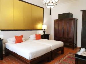 清迈Rachamankha Hotel的一间卧室配有带白色床单和橙色枕头的床。