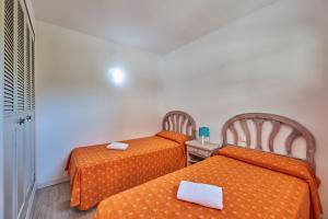 萨洛Inter Apartments的小客房内的两张床,配有橙色床单
