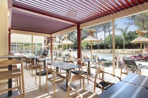 滨海卡瓦莱尔Résidence Prestige Odalys Les Canissons的一间带桌椅的餐厅和一个游泳池
