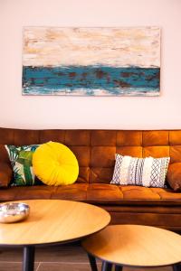莫甘My Pisito的一张带枕头的棕色沙发以及墙上的绘画作品