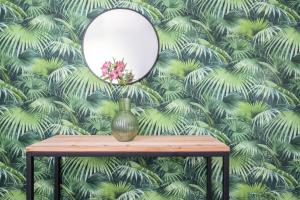 博洛尼亚Residence Studio Vita的一张桌子上的镜子,上面有绿色的绿叶壁纸