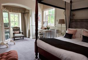 布罗肯赫斯特Careys Manor Hotel & SenSpa的一间卧室配有一张床、一张桌子和一把椅子