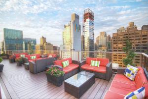 纽约Club Wyndham Midtown 45的屋顶甲板设有沙发和桌子,享有城市天际线